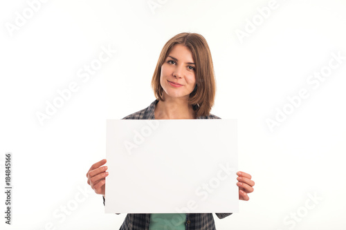 Young woman in green shirt holding sheet of paper and looking at camera. White background is not isolated.