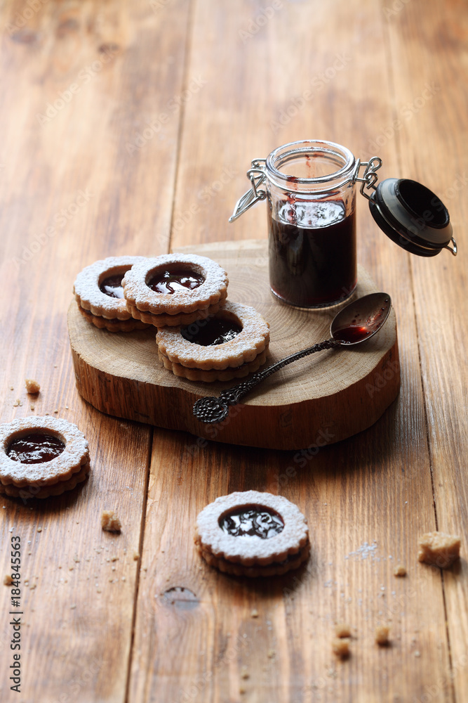 Vegan Jam Filled Sandwich Cookies on wooden board, little pot of jam, on wooden table. Vegan Jam Filled Sandwich Cookies on wooden board, little pot of jam, on wooden table.