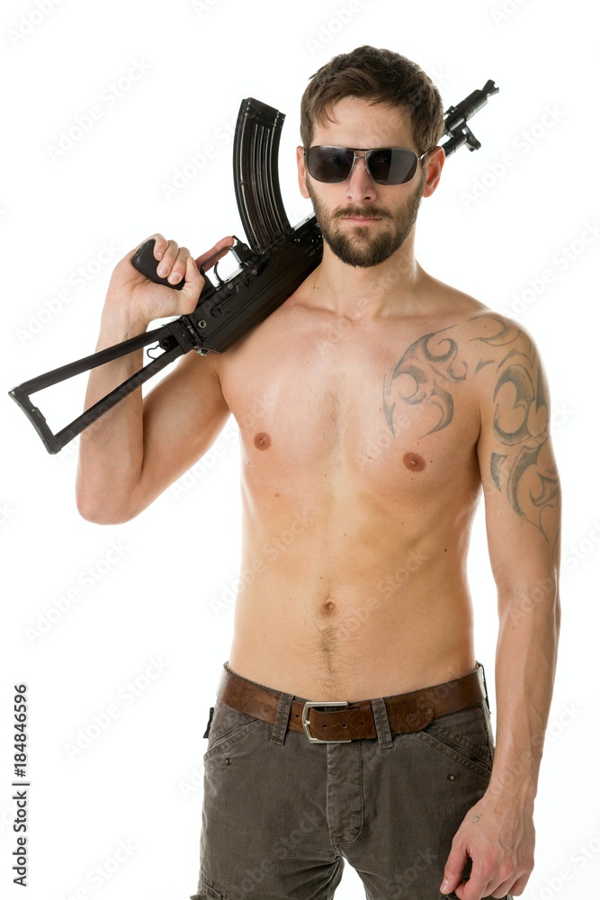 Man with a beard of a bandit with a naked torso with a Kalashnikov rifle on white background Man with a beard of a bandit with a naked torso with a Kalashnikov rifle on white background