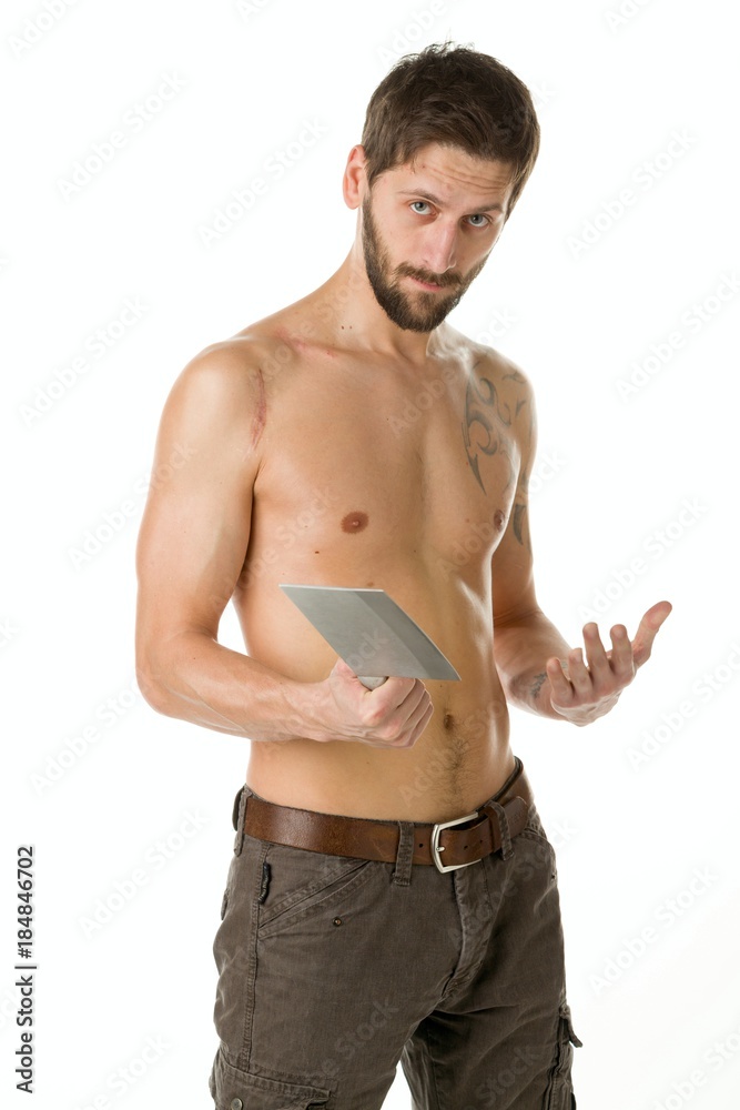 A man with a bandit's beard with a bare torso is holding a big knife in his hands against a white background A man with a bandit's beard with a bare torso is holding a big knife in his hands against a white background
