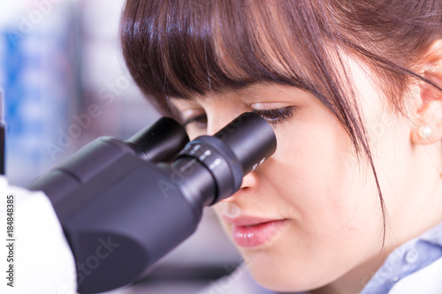 Doctor woman working a microscope. Female scientist looking through a microscope in lab. Student girl looking in a microscope, science laboratory concept
