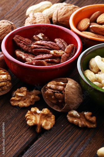 bowls with mixed nuts on wooden background. Healthy food and snack. Walnut, pecan, almonds, hazelnuts and cashews.