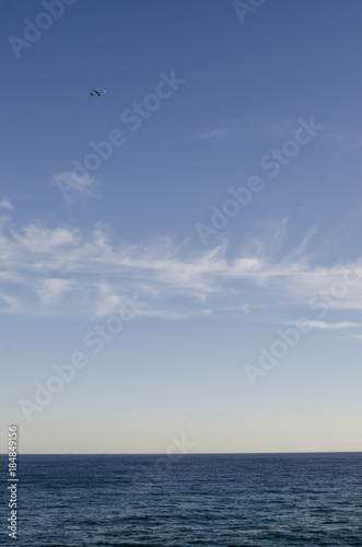 Blue clear water at mediteranean sea and clouds on sky and plane flying in background