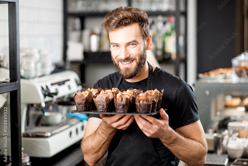 Ταπετσαρία Portrait of a handsome bearded confectioner in black t-shirt and apron holding m