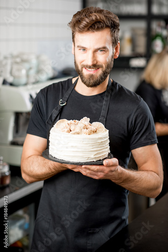 Konstfotografi Portrait of a handsome bearded confectioner in black t-shirt and apron holding a