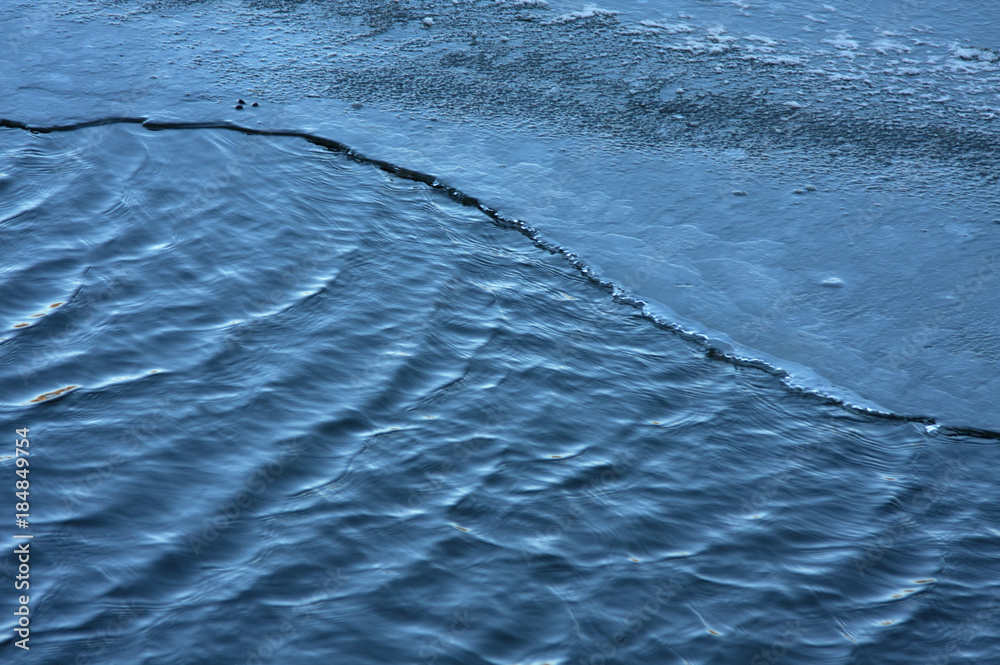 Φωτογραφία partially frozen river with a part of flowing water and part of the ice