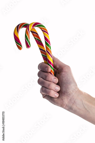 Female hand holds colorful candy canes on a white background. The isolated object
