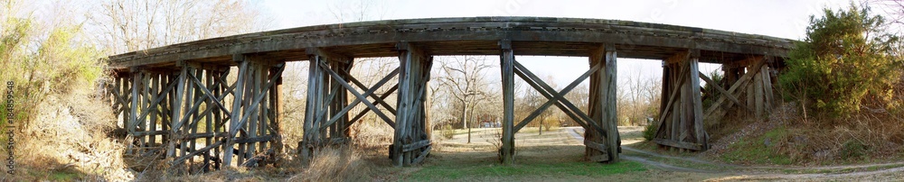 Obraz premium Wood Bridge at Sunset, Sunlight streams under the trestle, wide panorama.