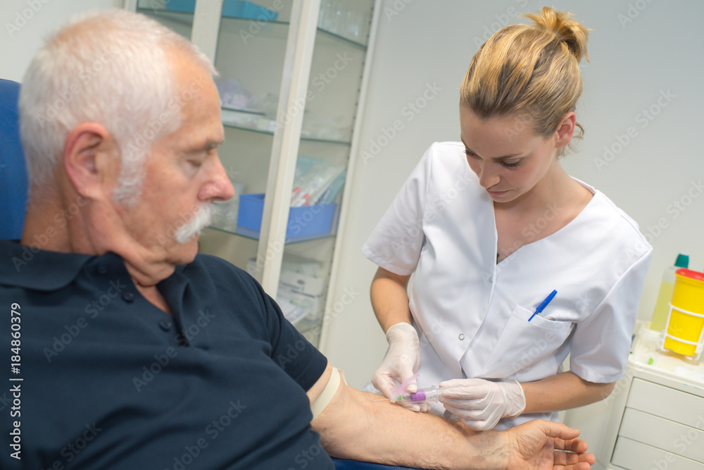Fototapeta premium nurse drawing blood sample from elderly male patient
