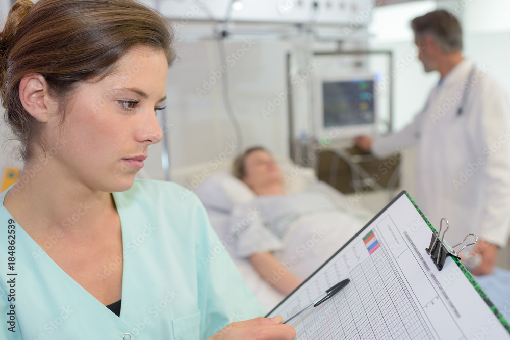 Fototapeta premium Nurse looking at chart on clipboard