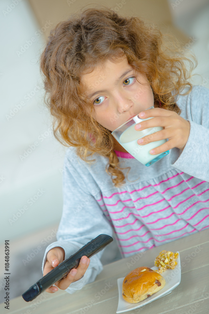 © auremar - Young girl having snack, holding remote control © auremar - Young girl having snack, holding remote control