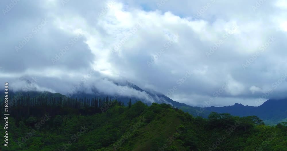 Aerial time lapse of mountain mists condensing and blowing up the steep tropical mountain cliffs, and joining the clouds rolling in and blanketing the dark green mountains. Aerial time lapse of mountain mists condensing and blowing up the steep tropical mountain cliffs, and joining the clouds rolling in and blanketing the dark green mountains.
