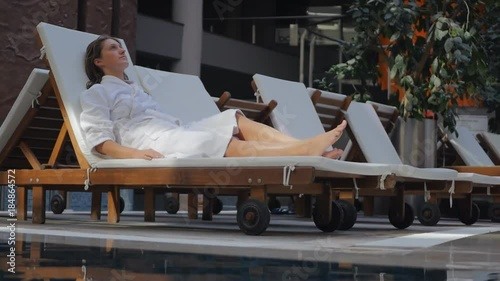 Young woman in bathrobe on the sunbed intdoors photo