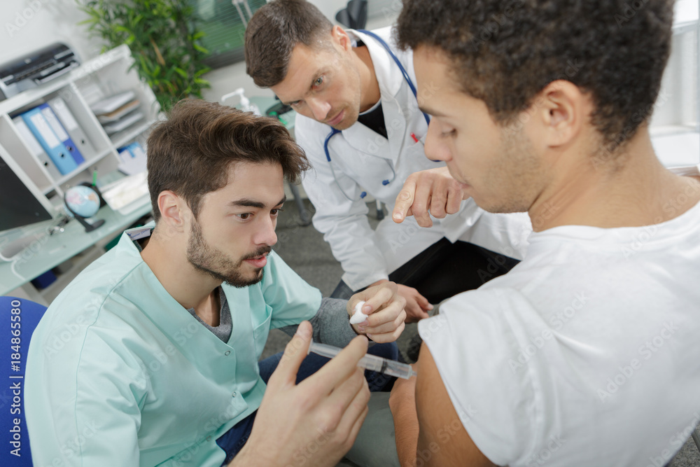 Fototapeta premium young male nurse giving intravenous therapy to patient