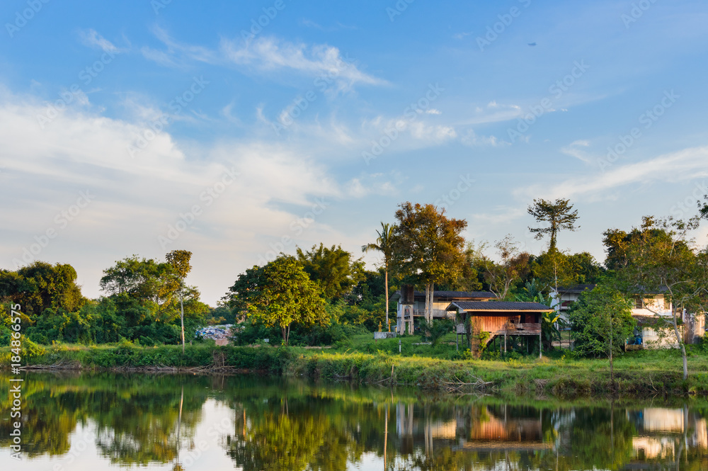 Wooden houses in countryside near the lake with mirror reflection in water