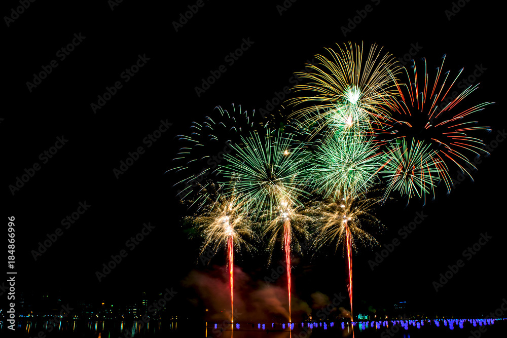 Beautiful fireworks in the night sky on the surface of the water in the park.