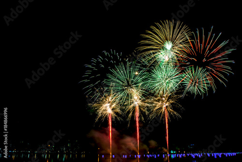 Beautiful fireworks in the night sky on the surface of the water in the park.