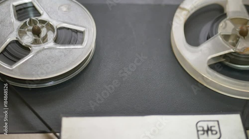 Old coil tape recorder with magnetic tape on reels. Reel with recording tape close up in reel-to-reel recorder. photo