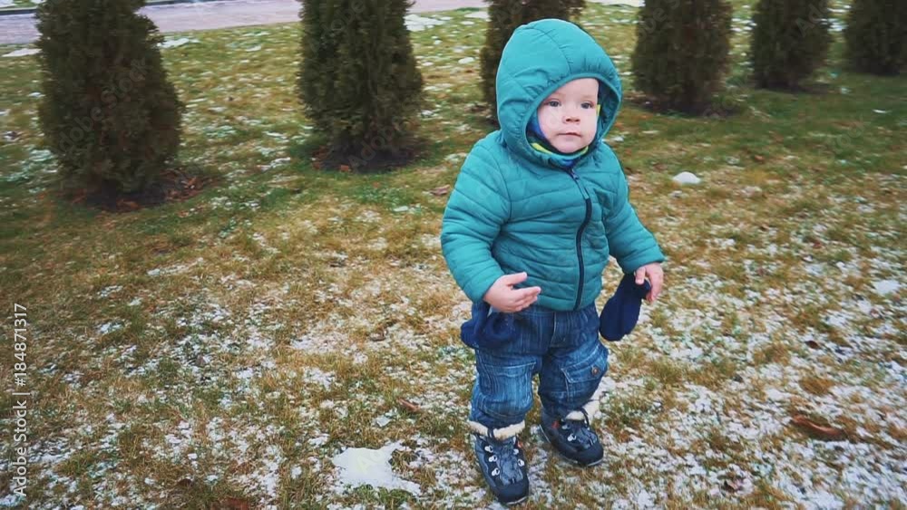 Spring. Steadicam shot of kid running down the sidewalk, grass and melting snow. slow motion Spring. Steadicam shot of kid running down the sidewalk, grass and melting snow. slow motion