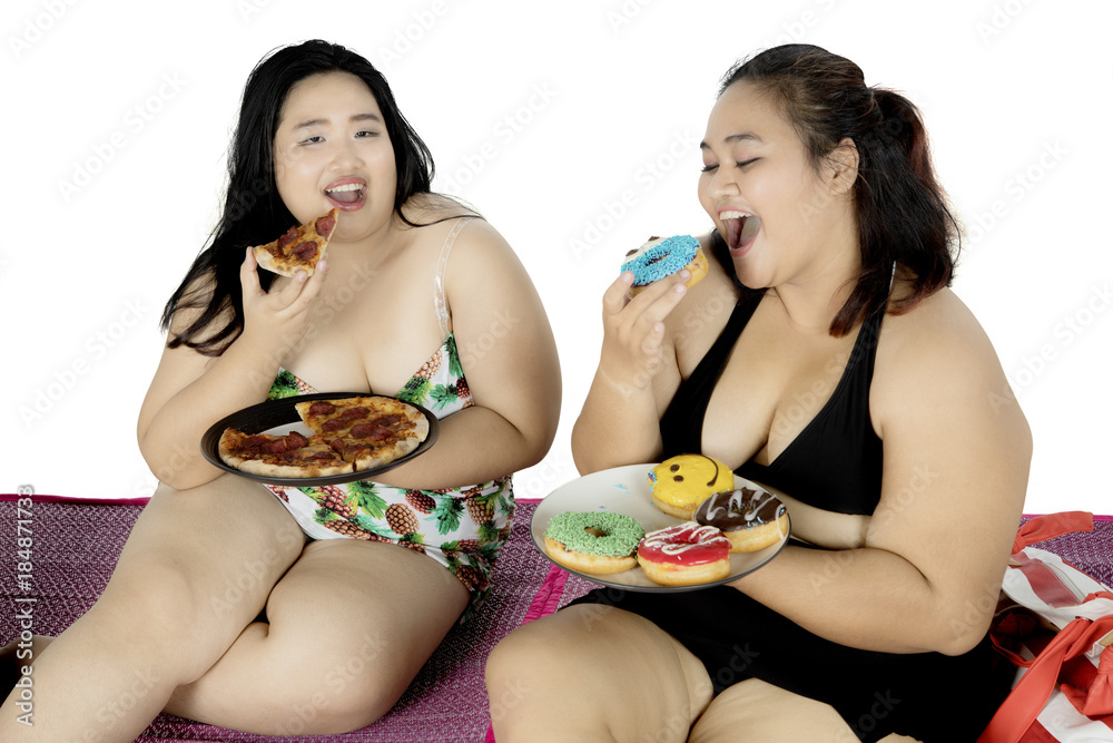 Two fat women enjoying meals at picnic time Two fat women enjoying meals at picnic time
