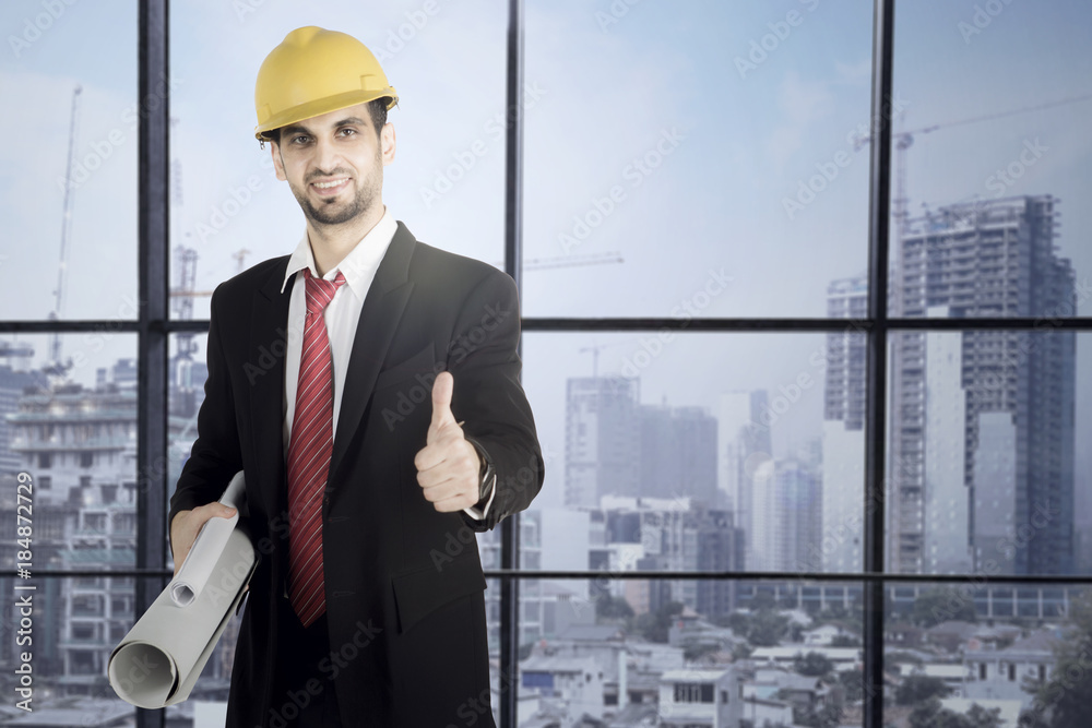 Fototapeta premium Businessman holding blueprints and showing thumb up
