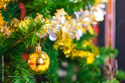 yellow ball hanging on the branch of Christmas tree on the background