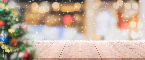 Wood table top on blur with bokeh Christmas tree background with snowfall - can be used for display or montage your products.