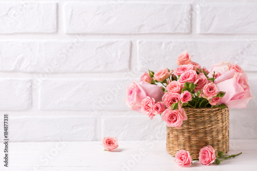 Background with pink roses flowers  against  white brick wall.