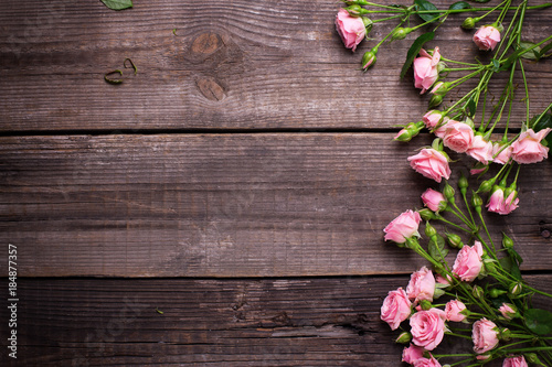 Border from tender pink roses flowers on aged wooden background