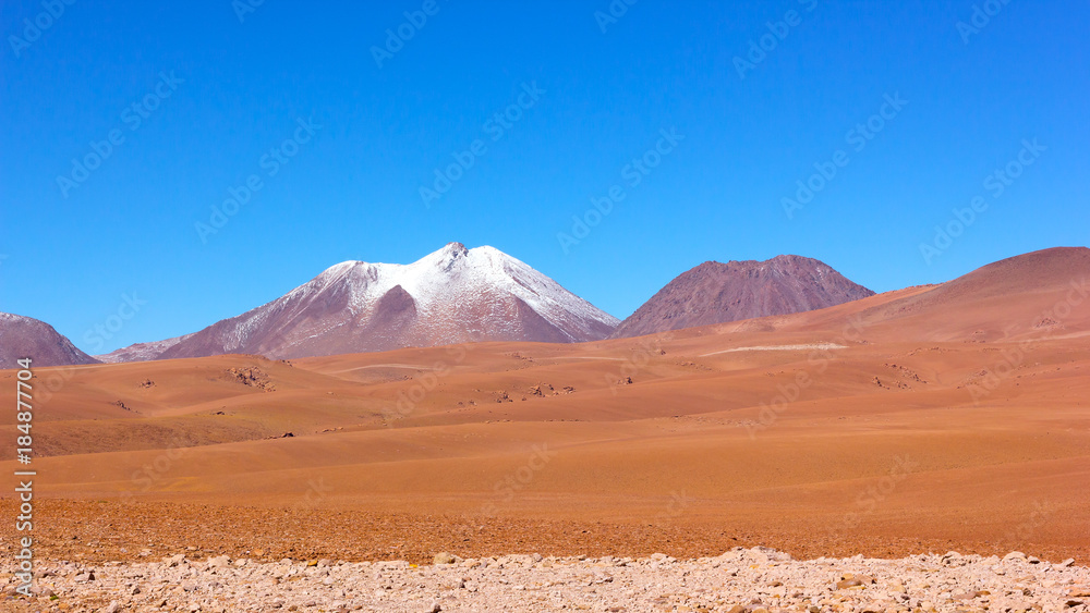 Natural beauty of unspoiled desert landscape. Colorful landscape of rocks, sandy valleys, and volcanic mountains with snow peaks in Atacama Desert, Chile.