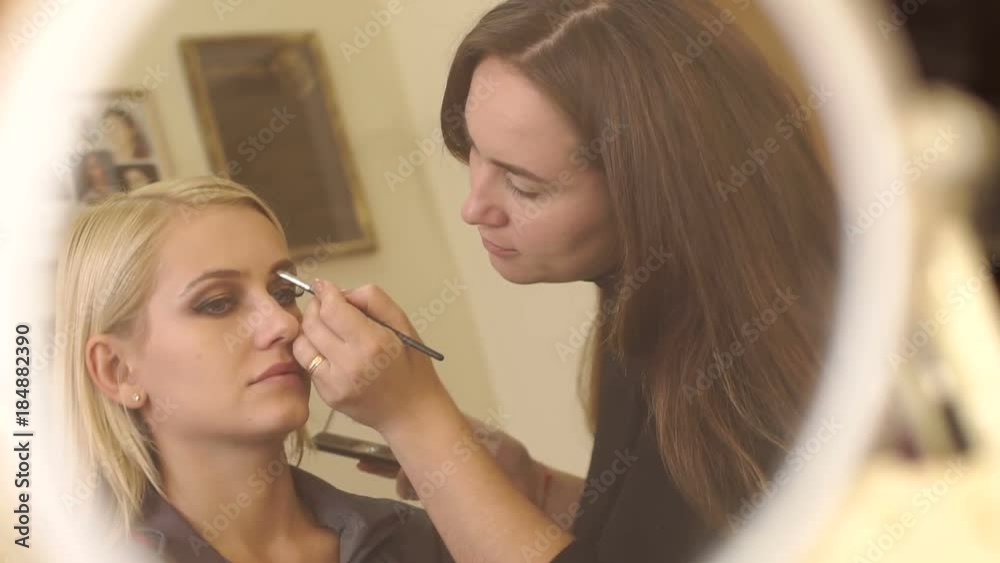 Reflection in the small mirror women Make-up artist which works with the client. Reflection in the small mirror women Make-up artist which works with the client.