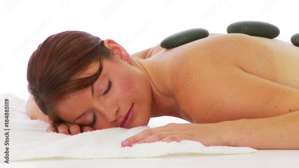 Woman laying facedown at spa with hot rocks on back Woman laying facedown at spa with hot rocks on back