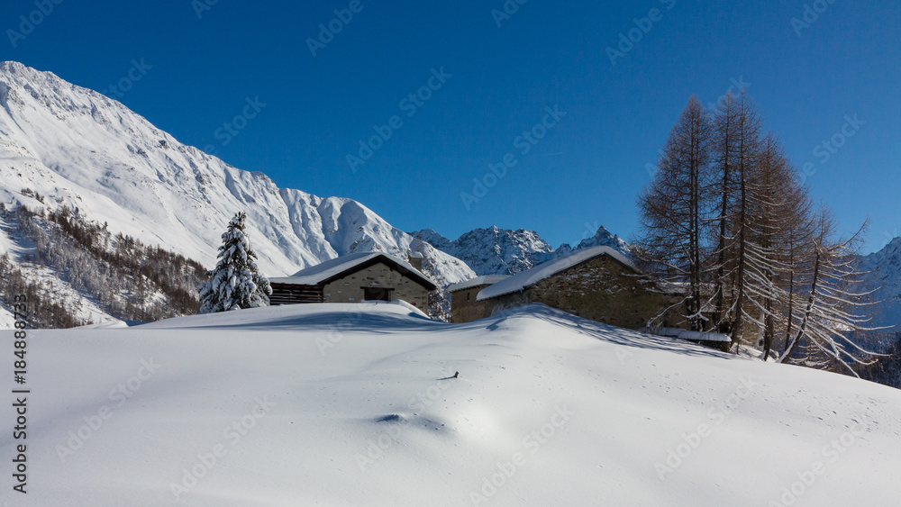 Little chalets in a forest covered with snow, winter landscape. Alps
