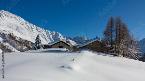 Little chalets in a forest covered with snow, winter landscape. Alps