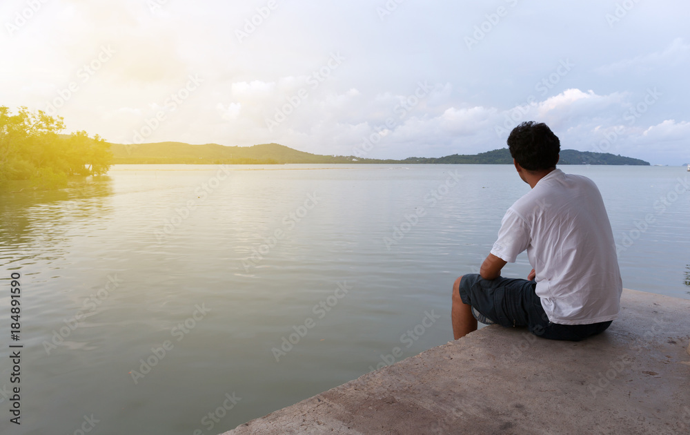 Lonely asian man sitting alone on a pier on sea in phuket thailand. Lonely asian man sitting alone on a pier on sea in phuket thailand.