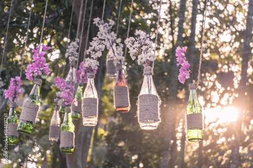 Fototapeta Naklejka Na Ścianę i Meble -  DIY decoration design for wedding romantic events with flowers in bottles, sunset warming the atmosphere, outdoors design ideas