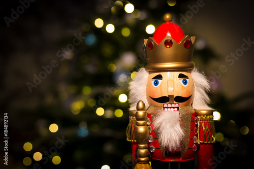 Christmas nutcracker with Christmas tree and lights in background