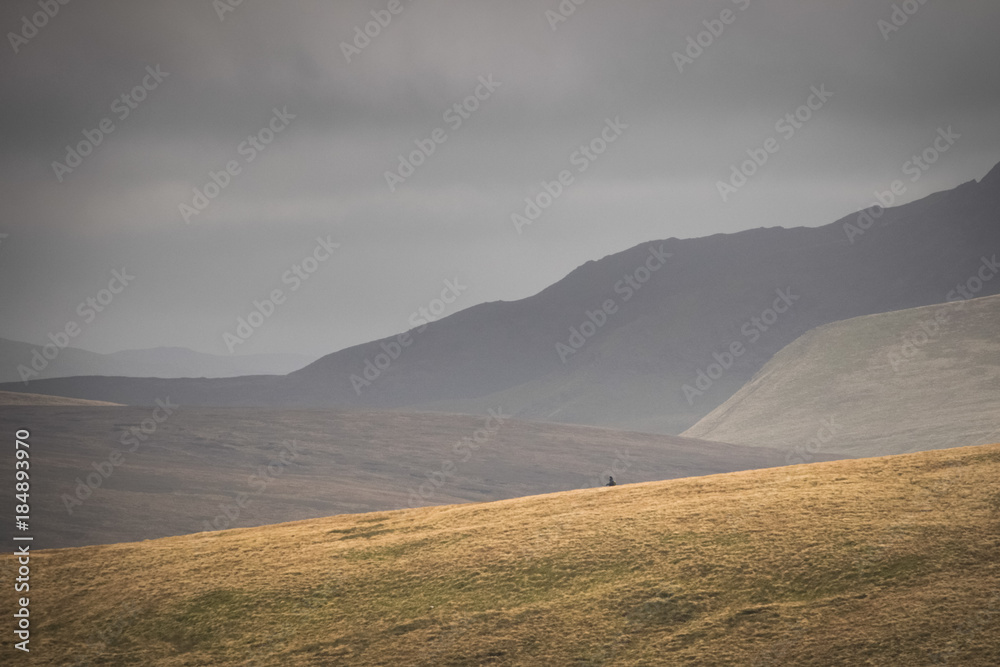 Hiker walking and felling small and humble inbetween the fells of the Lake district England