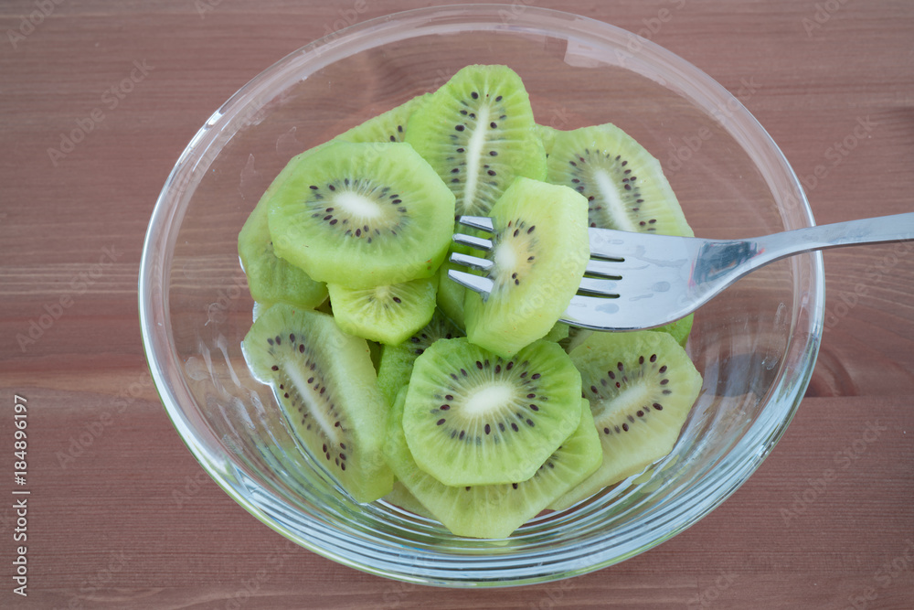 Bowl full with high in vitamins Kiwi slices isolated on wooden background Bowl full with high in vitamins Kiwi slices isolated on wooden background