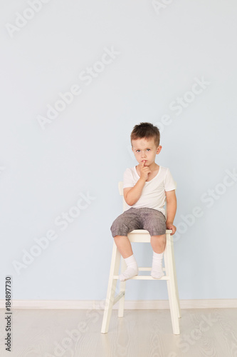 bright room. Boy in white shirt sitting in a high chair photo