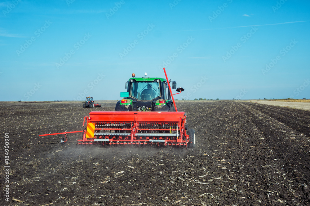 Naklejka premium Tractor with a roller on the field at spring