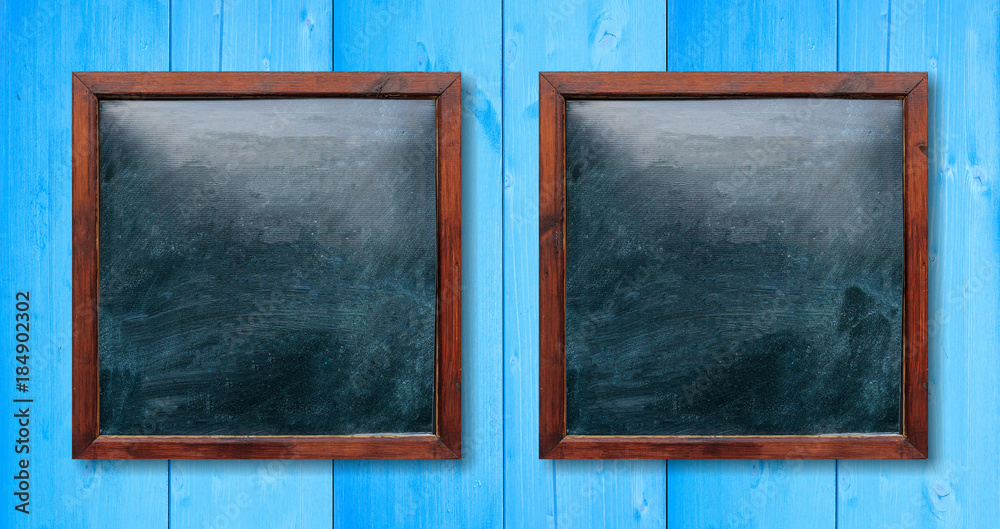 Empty wooden frames on the wall. Blackboards inside and light blue background, space for text. Empty wooden frames on the wall. Blackboards inside and light blue background, space for text.