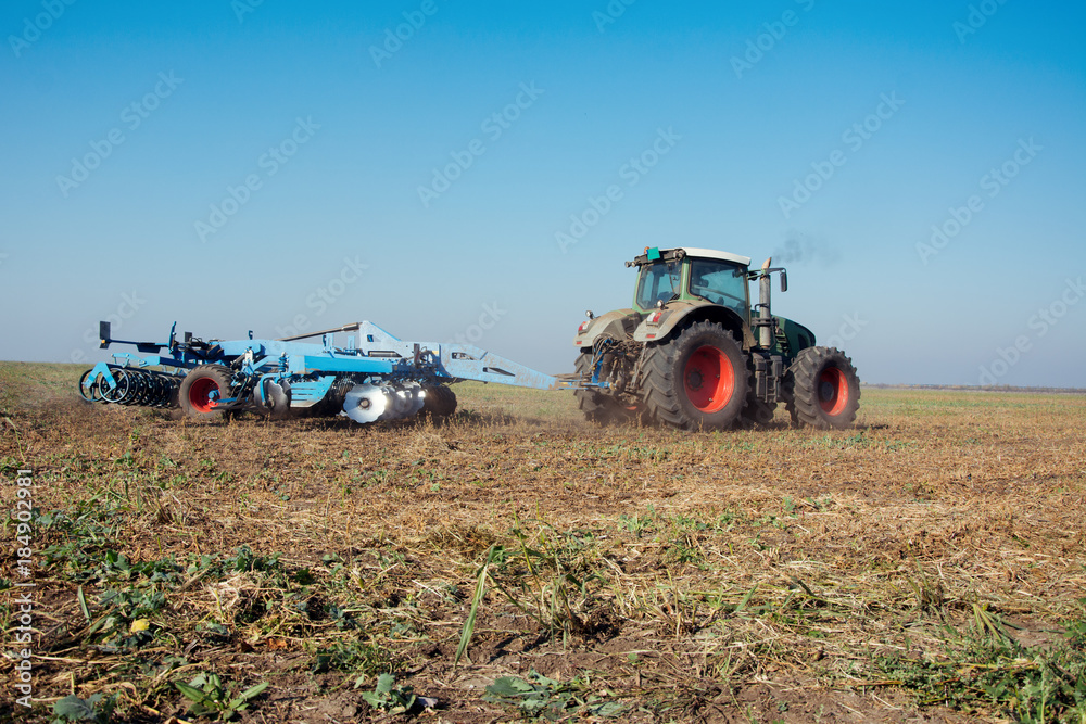 Modern tractor in a field on a sunny day. Tractor preparing land for sowing Modern tractor in a field on a sunny day. Tractor preparing land for sowing