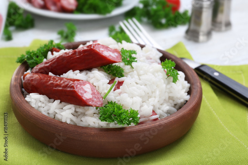 Wooden plate with rice and sausage on fabric