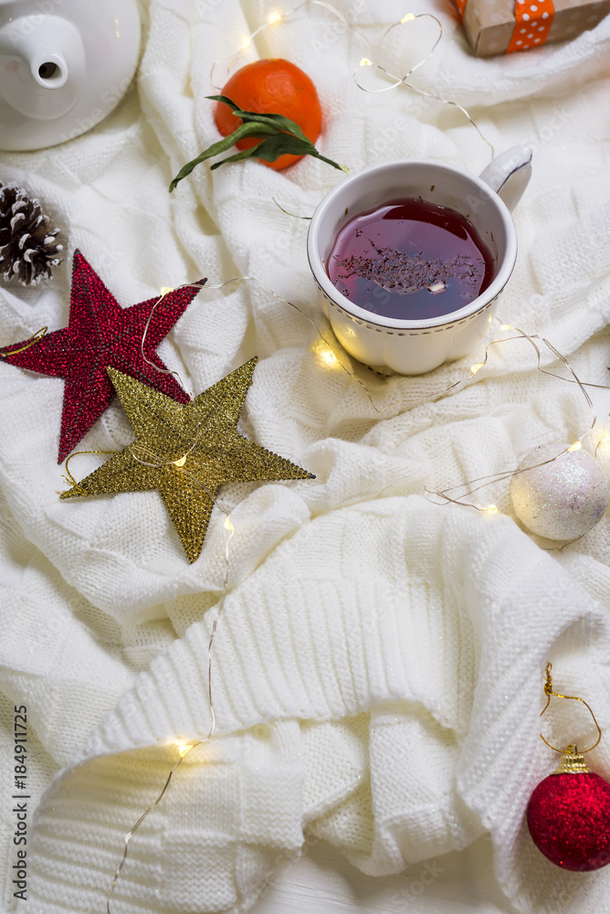 Hot Cup of tea with tangerines and sweaters on bed Hot Cup of tea with tangerines and sweaters on bed