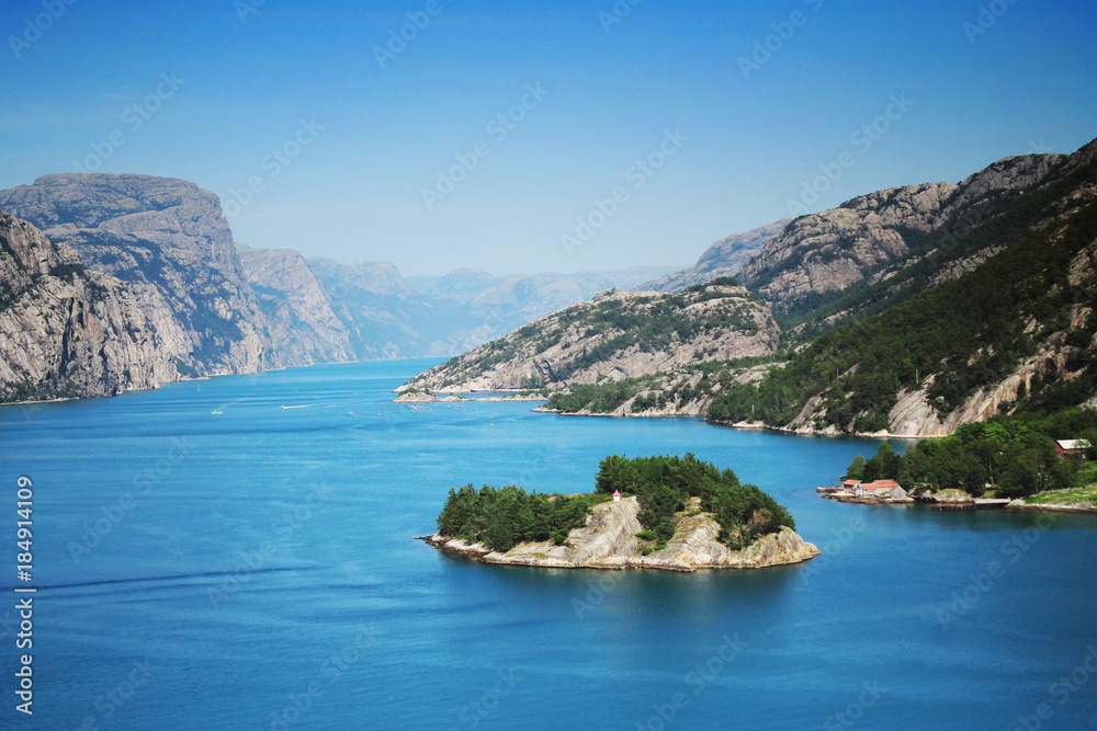 Sunny blue Norwegian fjord mountains with an island