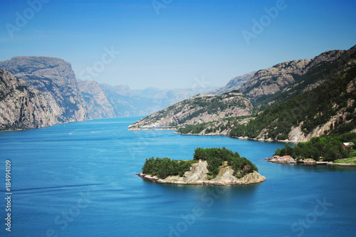 Sunny blue Norwegian fjord mountains with an island