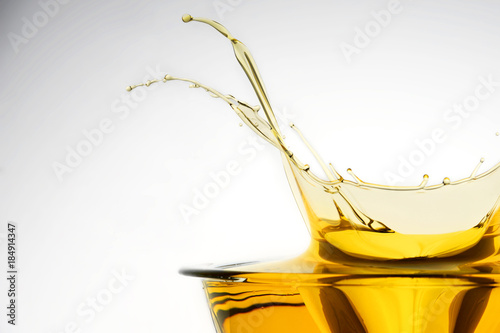 Side view of cooking oil splashing in container, studio background.