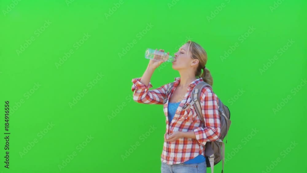 Female hiker drinking from bottle of water and exiting frame left Female hiker drinking from bottle of water and exiting frame left