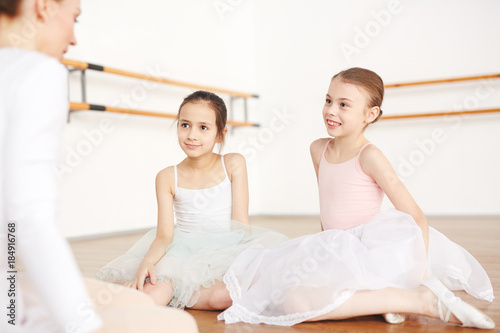 Cute little ballerinas listening to their teacher advice before stage performance